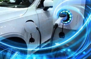 EV_Car_or_Electric_vehicle_at_charging_station_with_the_power_cable_supply_plugged_in_on_blurred_nature_with_blue_enegy_power_effect.-1