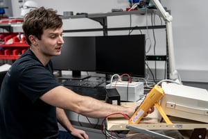 Ingénieur effectuant des mesures électriques sur un appareil électronique dans un laboratoire d'essais de produits